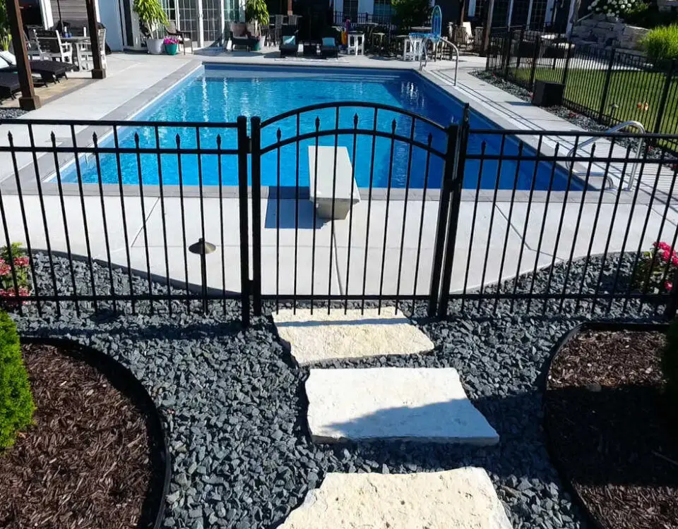 Black aluminum fence with a single arched gate surrounding a rectangular inground pool.