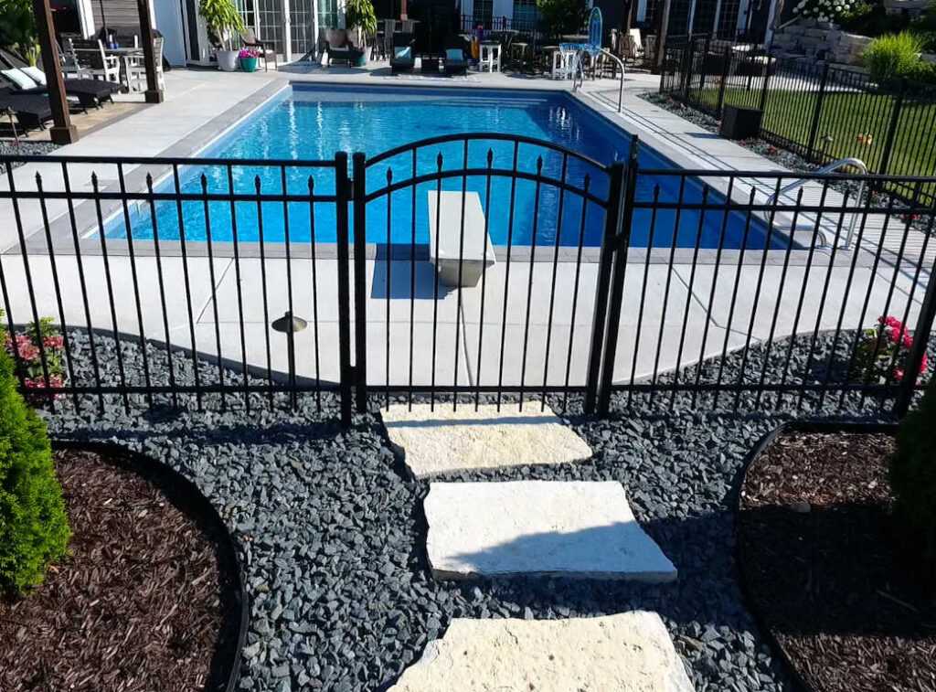 Black aluminum fence with a single arched gate surrounding a rectangular inground pool.