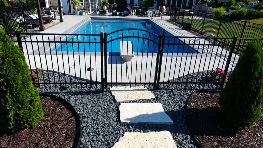 Black aluminum fence with a single arched gate surrounding a rectangular inground pool.